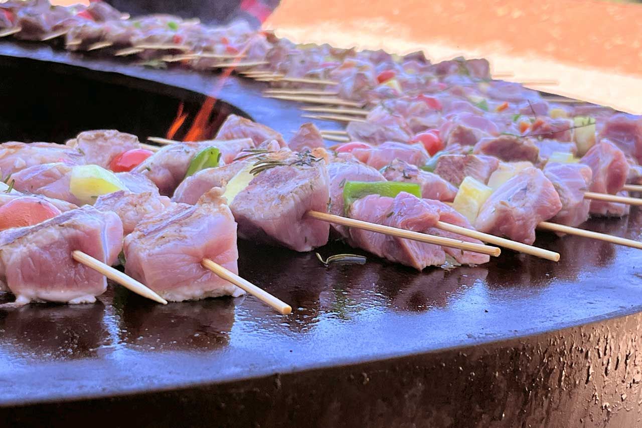 Cuisson à la plancha de brochettes de poulet à l'aide d'un feu de bois