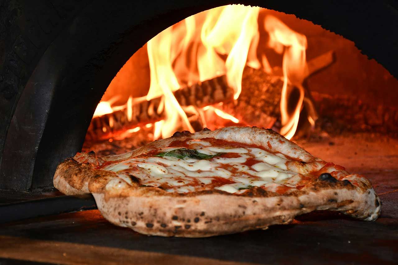 Une belle pizza cuite au feu de bois dans un four à pizza