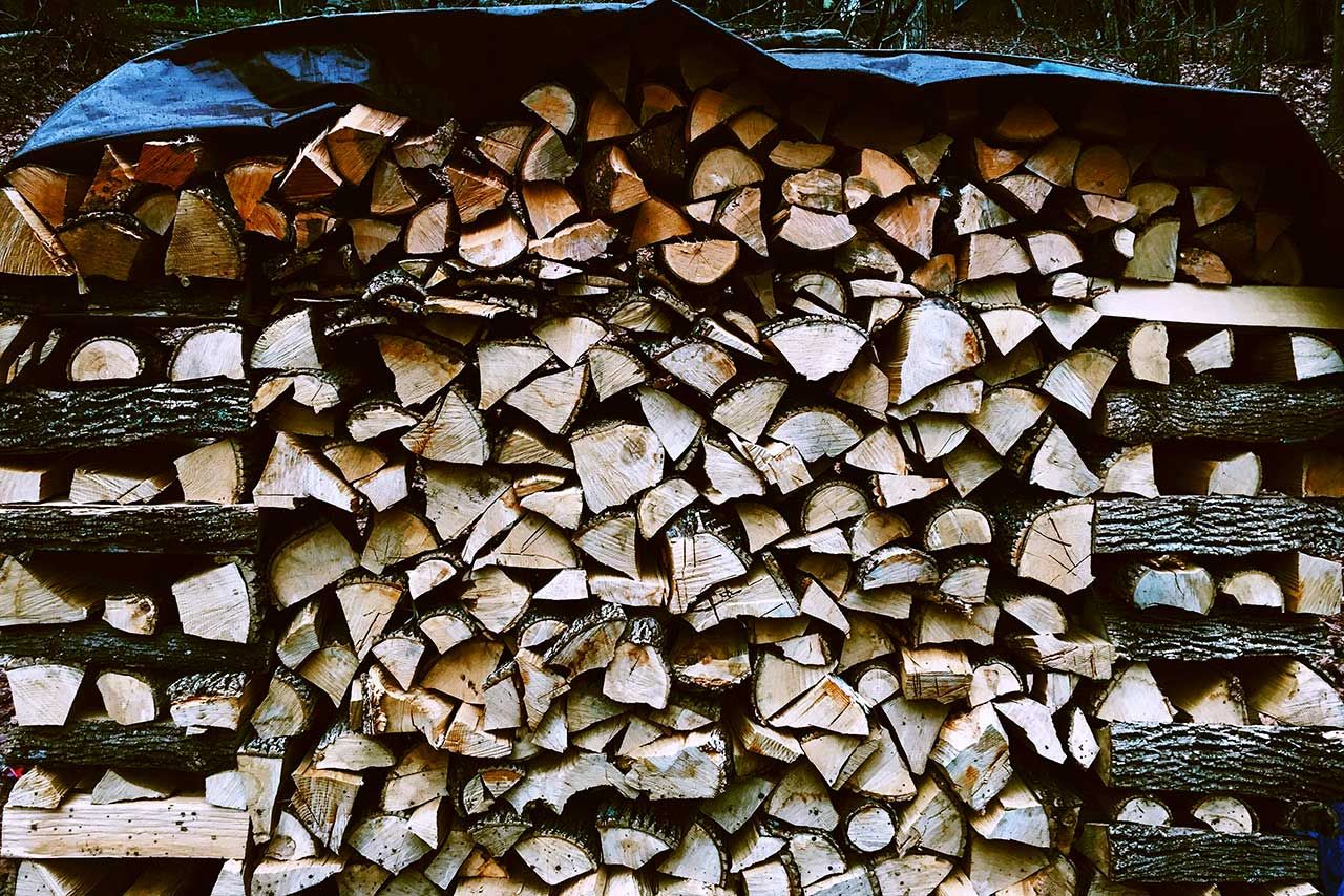 Stock de bûches de bois abritées sous un abri et une bâche