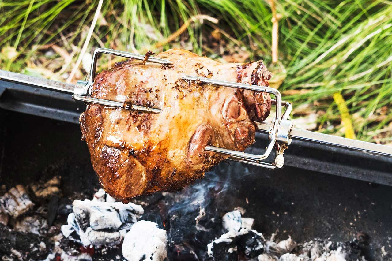 Cuisson d'un poulet au tourne broche ou rotissoire à l'aide des braises de bois chaudes